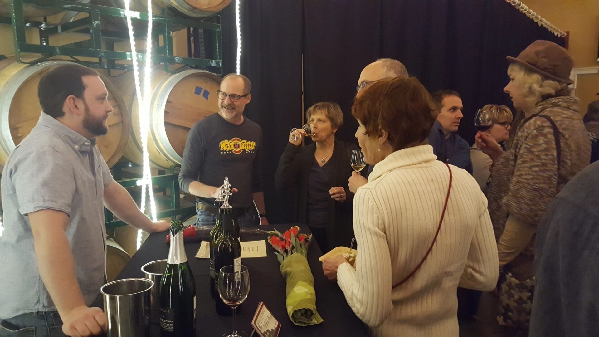 A group of people standing around a table with wine.