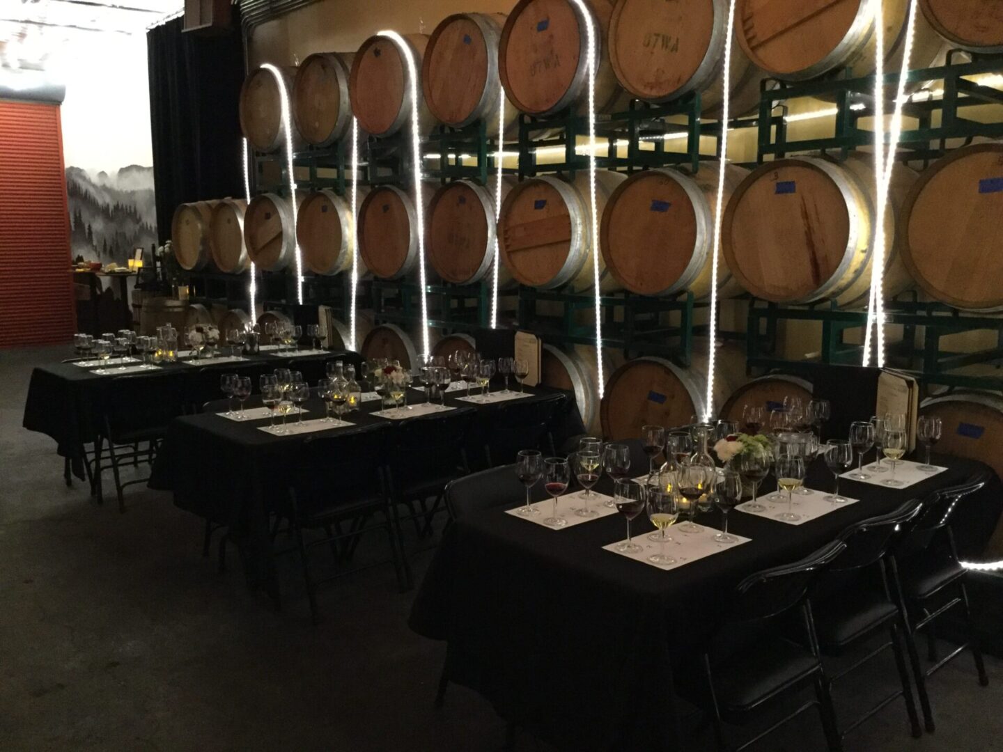 A room filled with tables and chairs next to wine barrels.