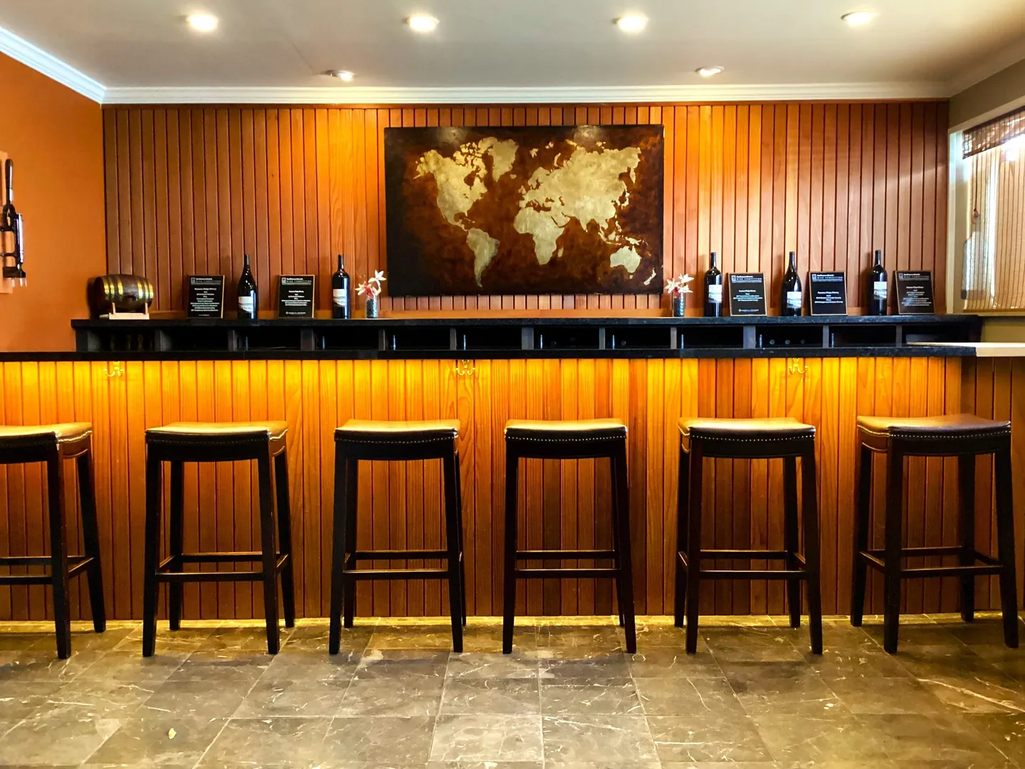 A bar with five stools and a map on the wall.