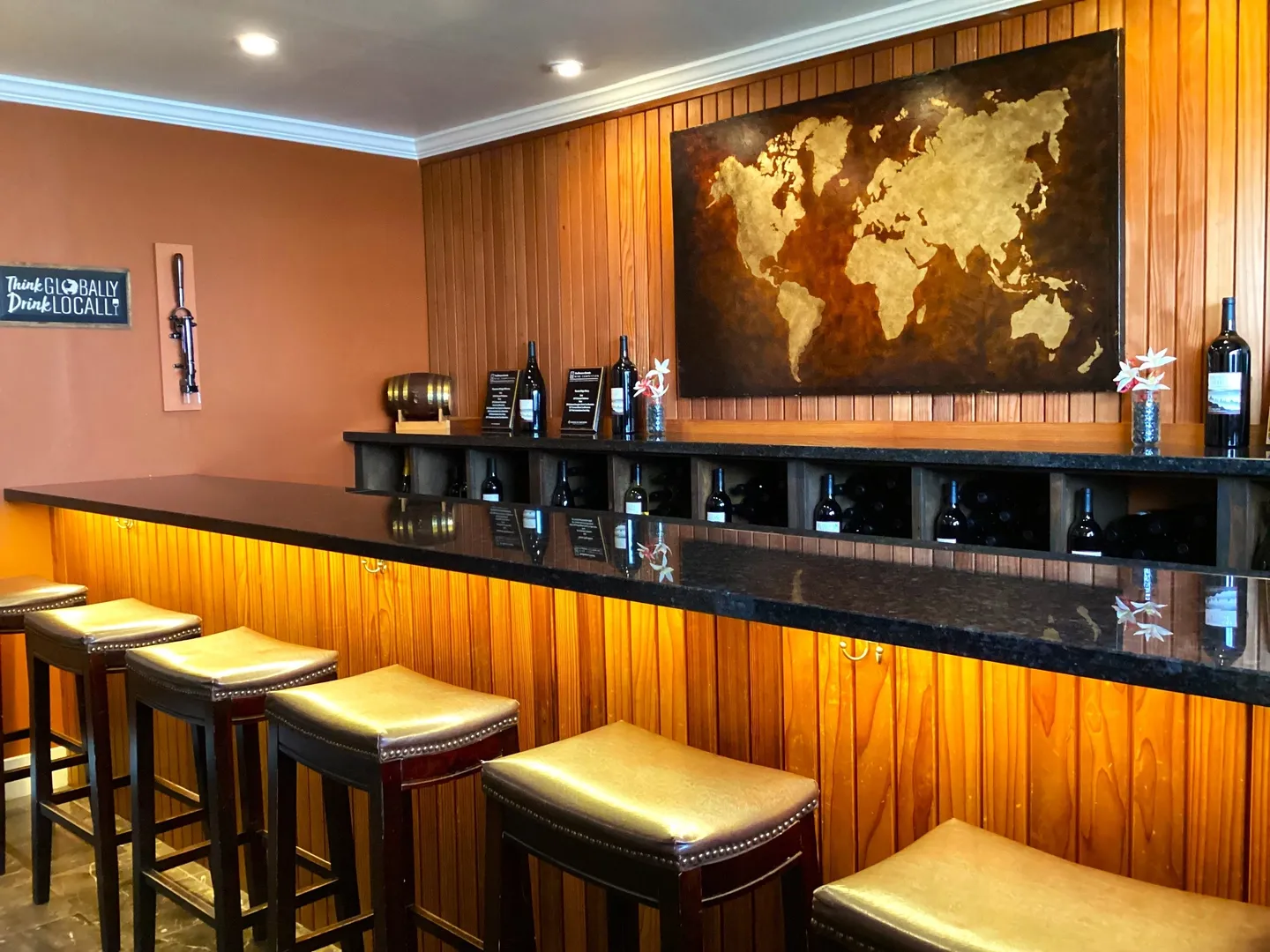 A bar with several stools and a map on the wall.