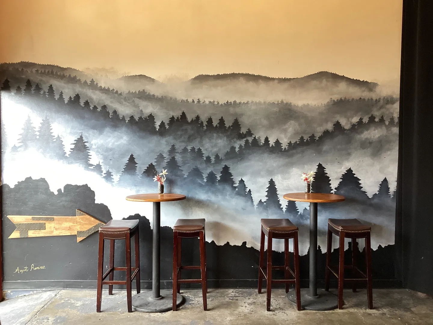 A room with three tables and chairs in front of a wall mural.